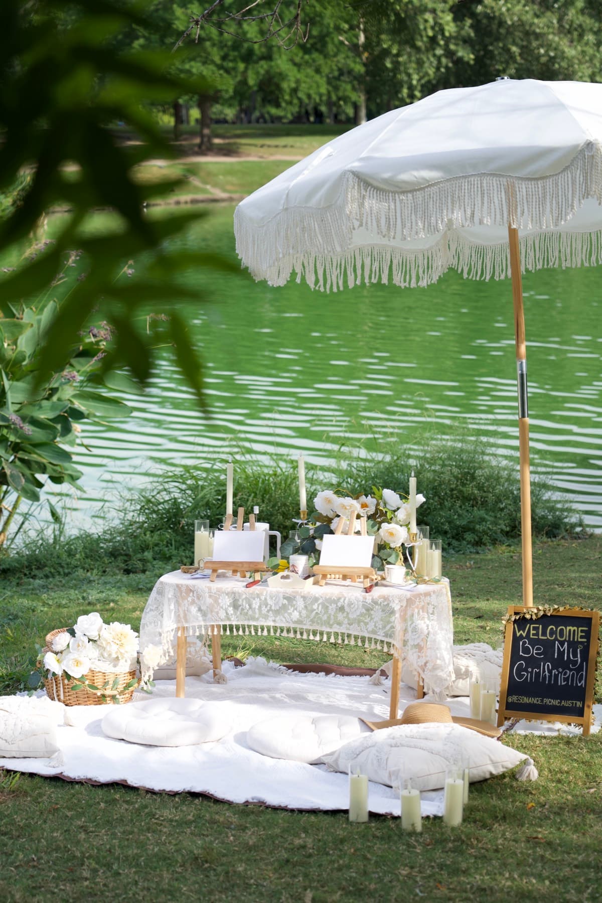 Romantic proposal picnic by the lake with a white fringe umbrella in Austin