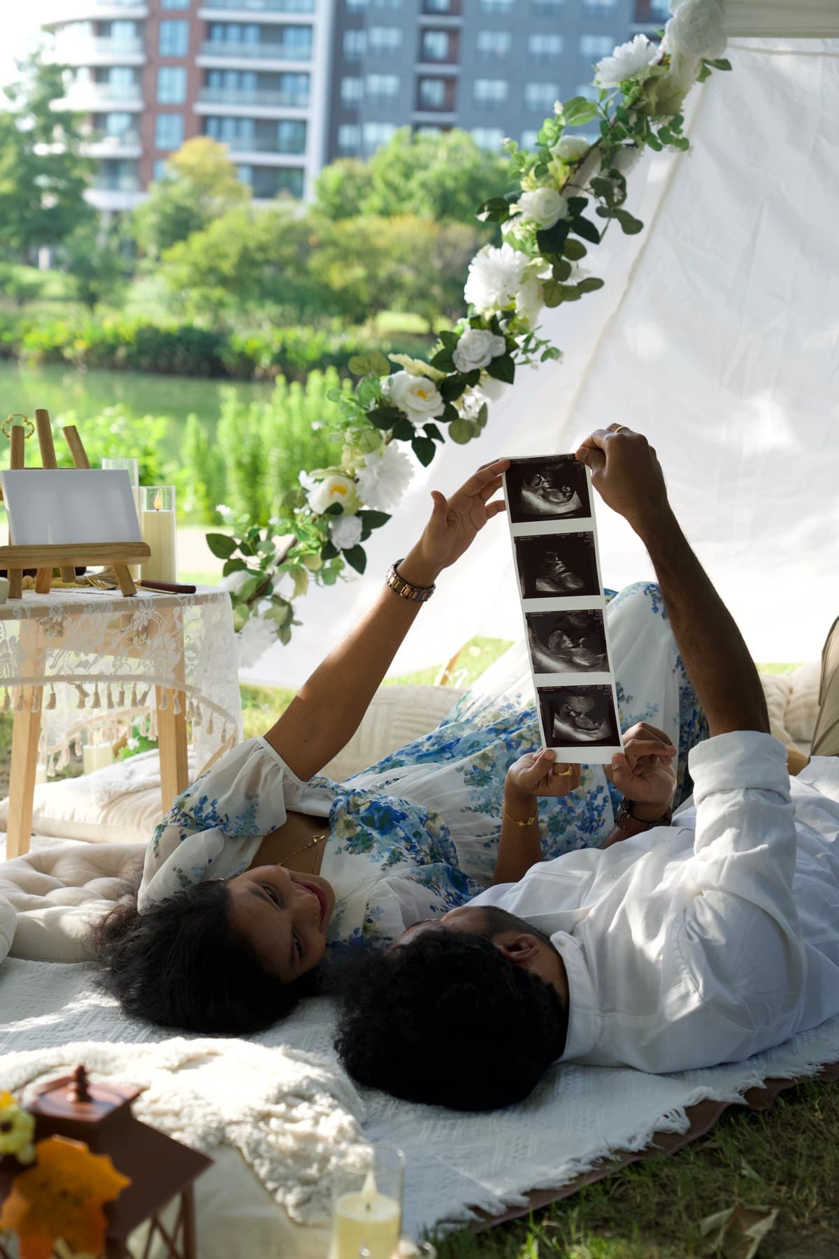 Couple sharing a pregnancy announcement with ultrasound photos at a lakeside picnic in Austin