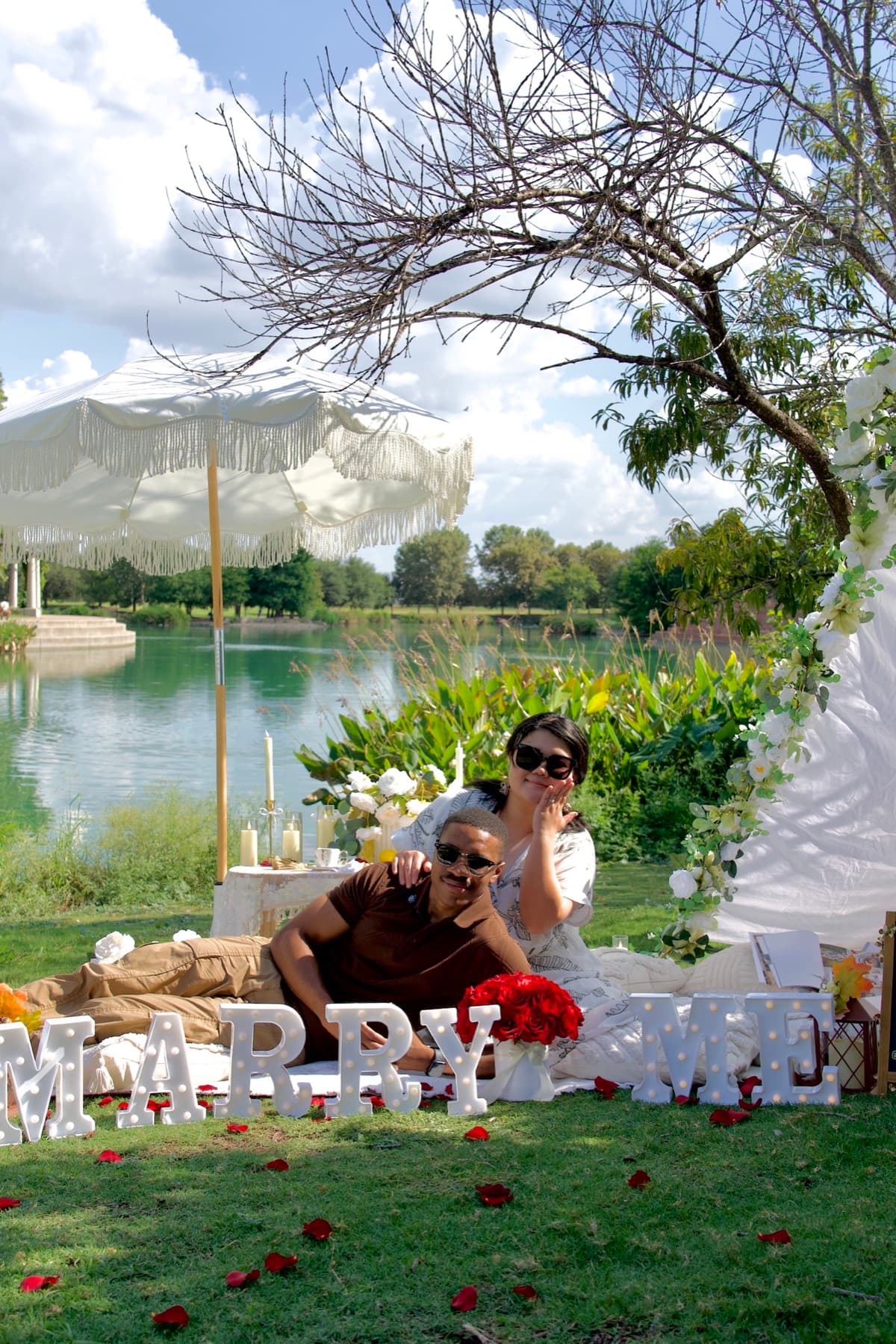 Couple celebrating their engagement with marry-me letters and rose petals in Austin