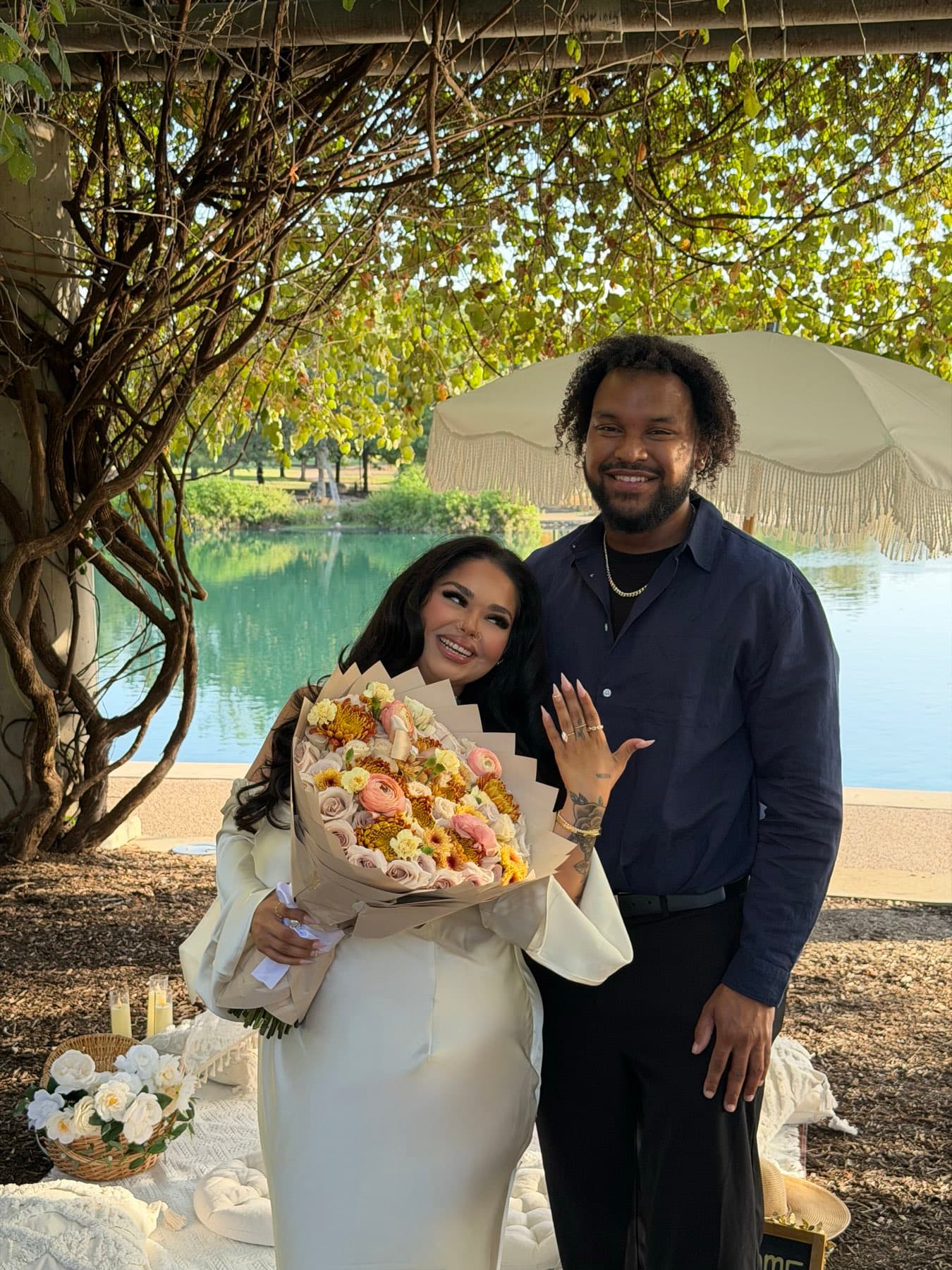 Just-engaged couple showing the ring with a pastel rose bouquet by the lake in Austin