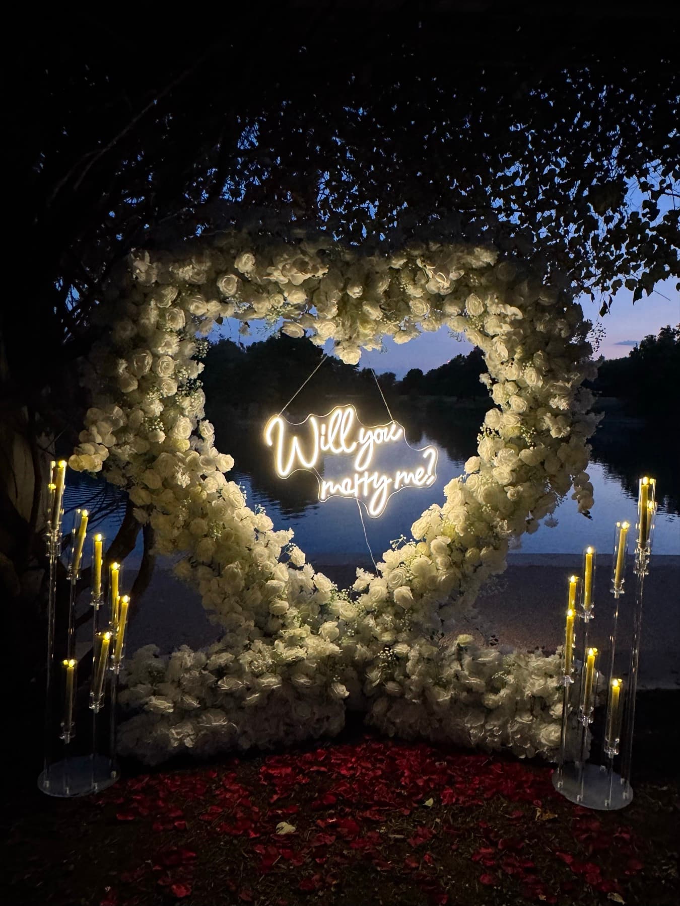 Heart-shaped white rose arch glowing at night with a will-you-marry-me neon sign in Austin